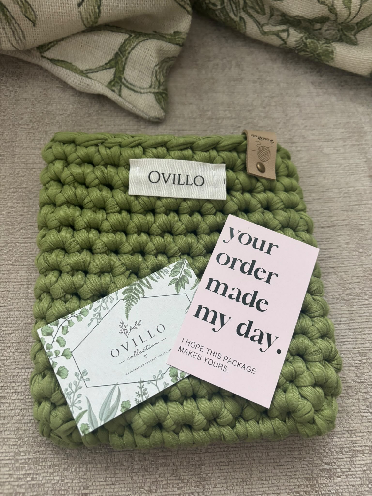 Close-up of a sage green crocheted piece and packaging